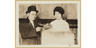 Historic photo of a Chinese woman casting her first vote next to a man in glasses and a bowler hat.