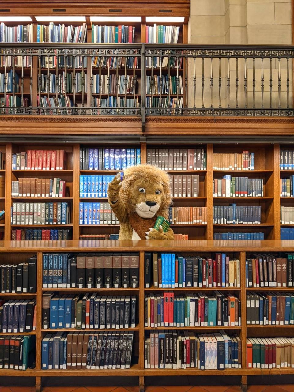 Library lion mascot taking a selfie in front of bookshelves