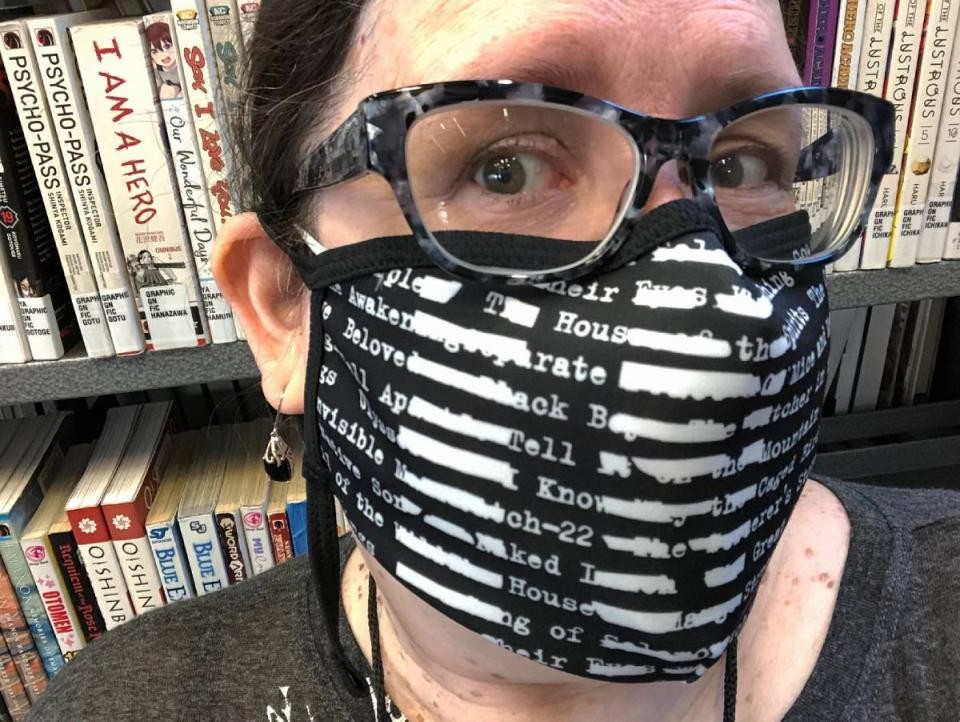 librarian in face mask posing on front of bookshelf