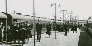 Historic photo of commuters walking on a platform between two trains.