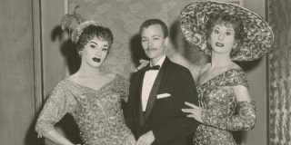 Historic black-and-white photo of Stormé DeLarverié in a tuxedo and bowtie flanked by drag queens in elaborate dresses