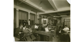 W.E.B. Du Bois and staff in the Crisis magazine office typing on typewriters and reading