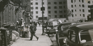 Historic photo of a NYC neighborhood with people walking around. 