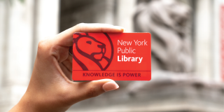 Hand holding a red NYPL library card that reads: The New York Public Library, Knowledge Is Power.