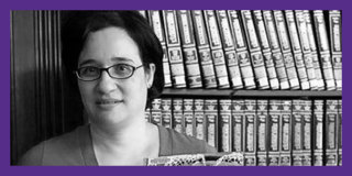 Black-and-white photograph of Roberta Saltzman in front of a full bookshelf. 