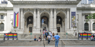 Exterior of the Stephen A. Schwarzman Building with rainbow Pride flag banners on display.